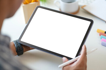 View over businessman shoulder hands using digital tablet at white working desk.