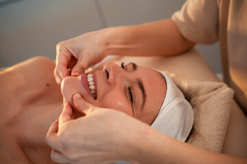 Fototapeta na wymiar Body massage treatment. Woman having face massage in the spa salon. 
