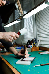 Hands of a professional craftsman make a leather wallet new, clean genuine leather wallet, close-up cropped shot.