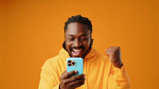 African man recieved good news via smartphone against yellow background