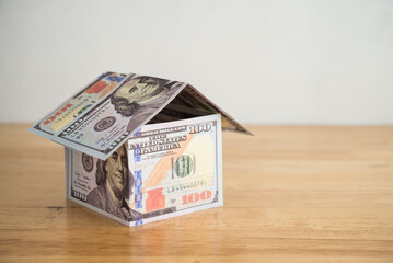 US banknotes bill paper house on wooden table with white wall background copy space. Mortgage loan for buying home or real estate property, money risk management in financial, foreclosure and bankrupt