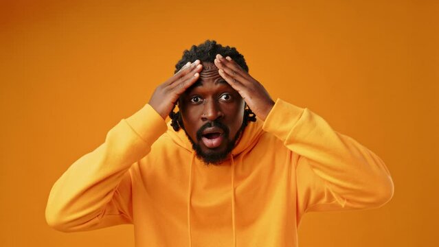Portrait of shocked young African man on yellow background