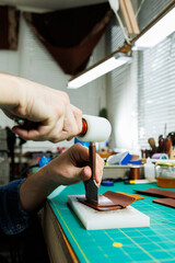 The hands of the master sew handmade leather products. Men's hands connect the parts, creating quality leather accessories. Working process in a leather workshop
