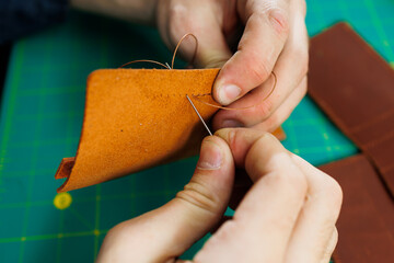 Close-up of male hands working with natural leather. Handmade products made of genuine leather.