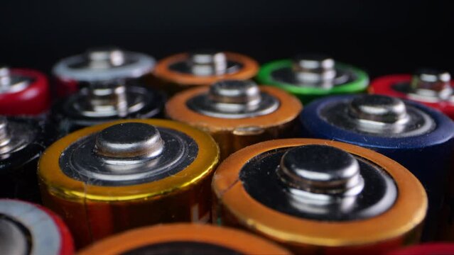 Close-up of old alkaline batteries, commonly used in toys and small appliances. Shot in macro against a dark background.