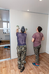 Workers install plasterboard wall in the room