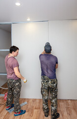 Fototapeta na wymiar Workers install plasterboard wall in the room