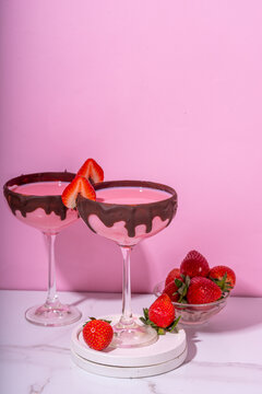 Sweet chocolate strawberry cocktail, cute pink strawberry martini or daiquiri creamy drink, with fresh strawberry garnish and choco drizzles, on high-colored pink background