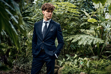 Handsome young man in blue suit posing in garden