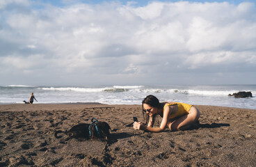 Woman taking photo of dog on beach