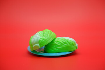toy cabbage and blue plate isolated on red background. Attachable and detachable cabbage vegetable toy.