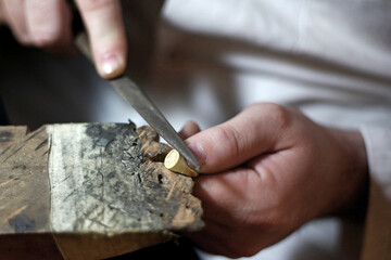 Bijoutier en train de polir une bague en or dans son atelier