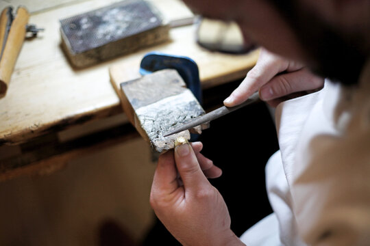Bijoutier en train de polir une bague en or dans son atelier