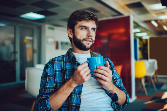 Thoughtful man with cup of coffee in office