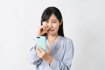 スマートフォンを持ちながら泣く若い女性