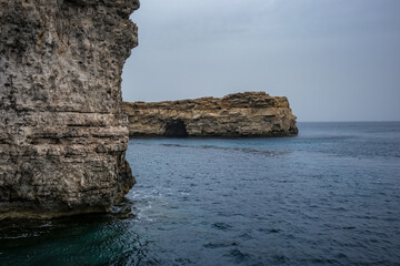 Naklejka premium View from around Comino island, Malta. Scenery rocks in the Mediterranean sea. Moody spring time weather, cloudy day.