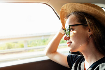 Woman sitting in car and looking out the window, taxi service. © Barillo Images