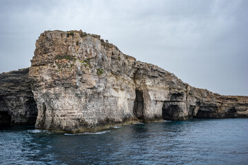 View from around Comino island, Malta. Scenery rocks in the sea. Moody spring time weather, cloudy day.