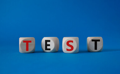 Obraz premium Test symbol. Concept word Test on wooden cubes. Beautiful blue background. Business and Test concept. Copy space.