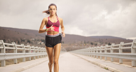 Female athlete running at a bridge