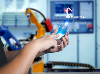 Businessman holding smartphone with pushing command button to control AI system to control machine operation in industry 5.0 concept to AI system control future machines