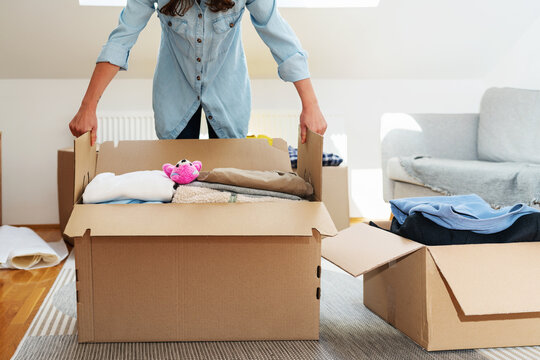 Female person packing clothes for charitable giving.