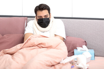 Sick man lying in the bed, suffering from high fever and flu. He tries to treat himself at home	