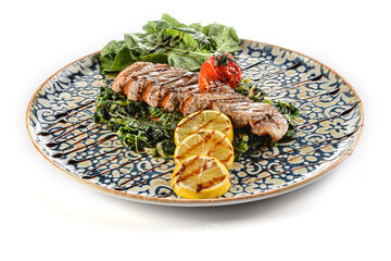 Grilled salmon on a bed of spinach with tomatoes, arugula and lemon