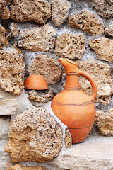 Georgian traditional clay vessel for wine and piala near old stone wall, street decor