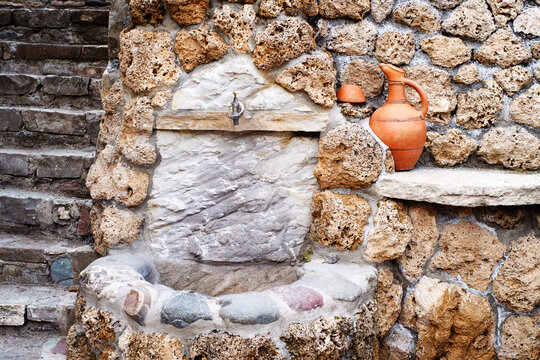 Georgian traditional clay vessel for wine and piala near old stone wall, street decor