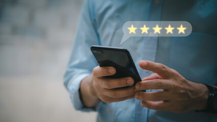 Customer service experience and business satisfaction survey.close up Man hand using smartphone with popup five star icon for feedback review satisfaction service.