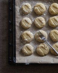 Round pieces of dough on baking paper on baking pan, top view. Homemade cookies preparation