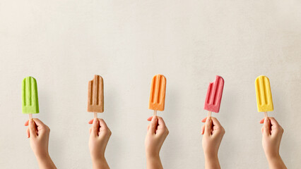 Hands holding different types of colorful fruit popsicles - Powered by Adobe