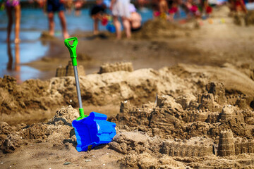 Piaszczysta plaża z zamkami na piasku i zabawkami. 