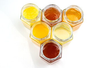 jars with different types and colors of honey on a white background. organic vitamin food