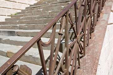 Detail of an historical old italian chiseled stone staircase with wrought iron railing and stone...
