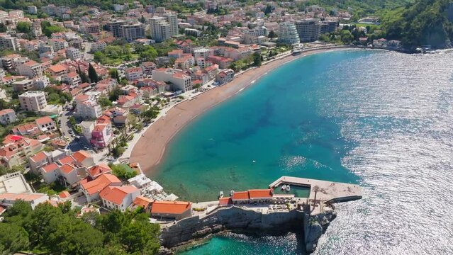 Aerial view - Petrovac city in Montenegro, summer sunny day. Sandy beach and mountains in shot