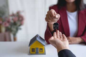 Young woman taking key from a female real estate agent during a meeting after signing a lease or sale contract