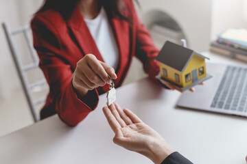Young woman taking key from a female real estate agent during a meeting after signing a lease or sale contract