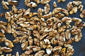 Peeled nuts without shells lie on a black tray