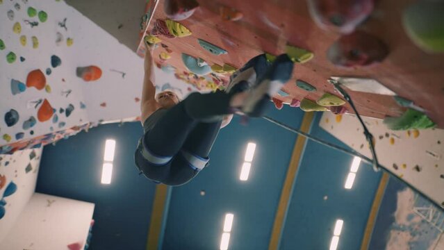 Young woman rope climbing in indoor climbing centre