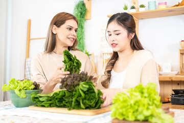 Smiling women preparing fresh healthy salad vegetables. woman sitting at pantry in a beautiful...