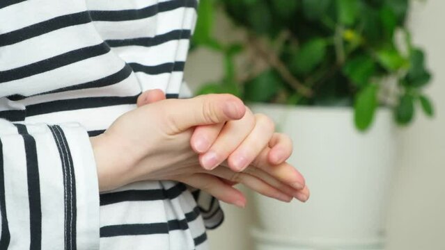 A woman wrings and rubs her fingers, anxiety and stress, palms sweat.