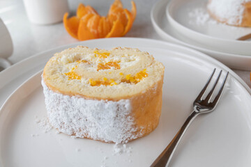 Swiss roll or biscuit roll with whipped cream and mandarin filling sliced on a plate