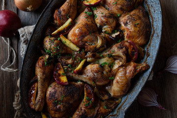 Sunday or holiday chicken meat dish with roasted apples and onions in roasting pan for autumn and winter season