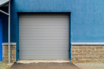 Fototapeta na wymiar grey garage door on a blue plastered wall