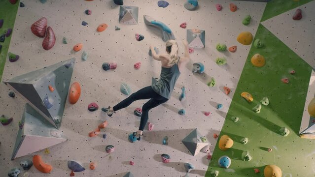 Young woman practicing bouldering on an indoor climbing wall