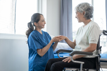 Asian senior care nurses and grandmothers provide caring support to elderly women hand clasp to encourage exercising with elder disabled person patient with caregiver in nursing care.