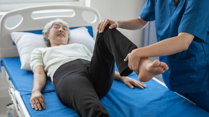 Obraz premium Asian female physiotherapist helping senior older woman stretching hamstring, Rehabilitation physiotherapy, elderly. Causes knee pain, swelling, redness, stiffness in knee, clunking noise in knee.
