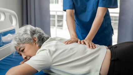 Asian female physiotherapist doing elderly asian gray haired female patient chiropractic pain...